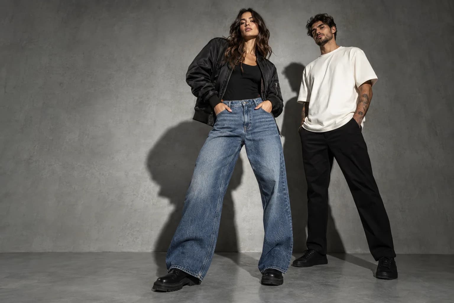 Modelos com jaqueta bomber preta, jeans azul e camiseta oversized na campanha demonstrativa Look & Like